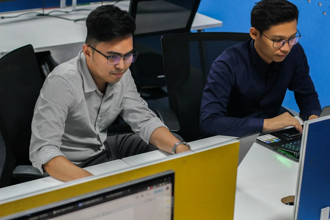 Two developers working side by side at their desks