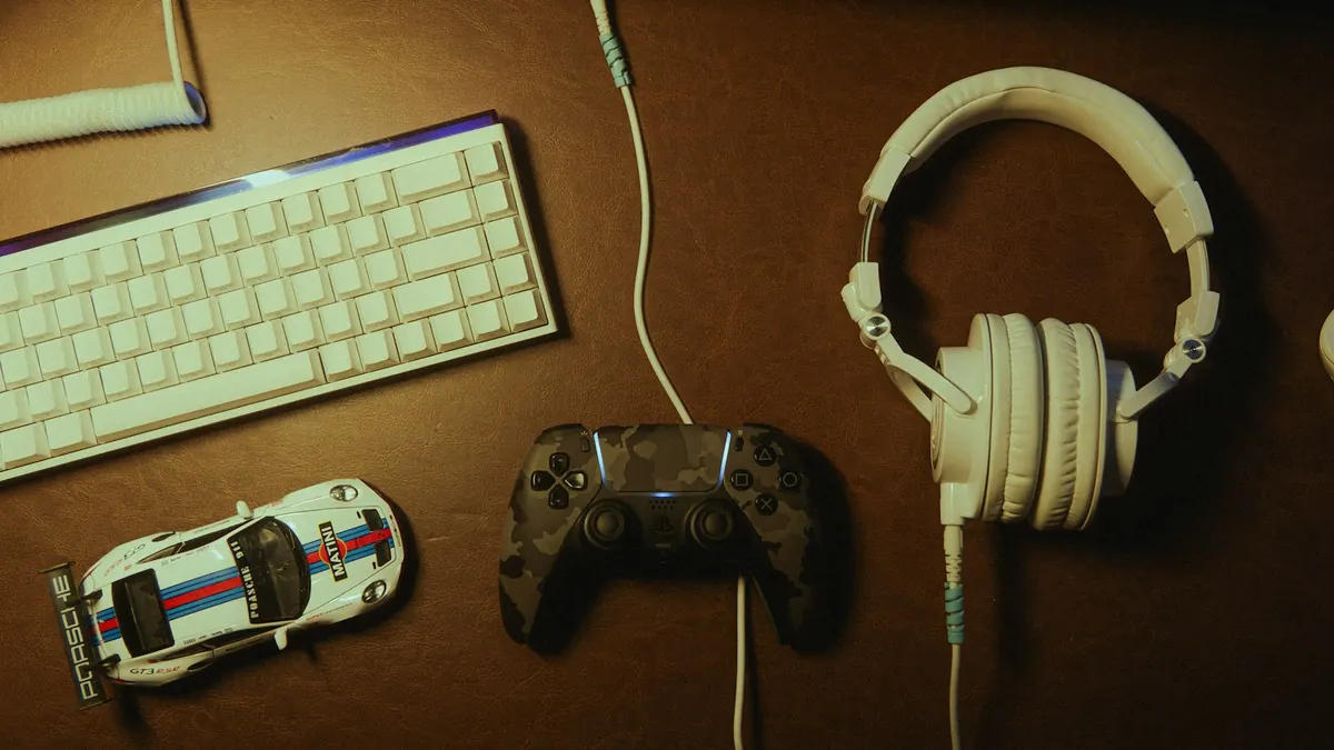Keyboard, controller, headphones and toy car laid out on a desk
